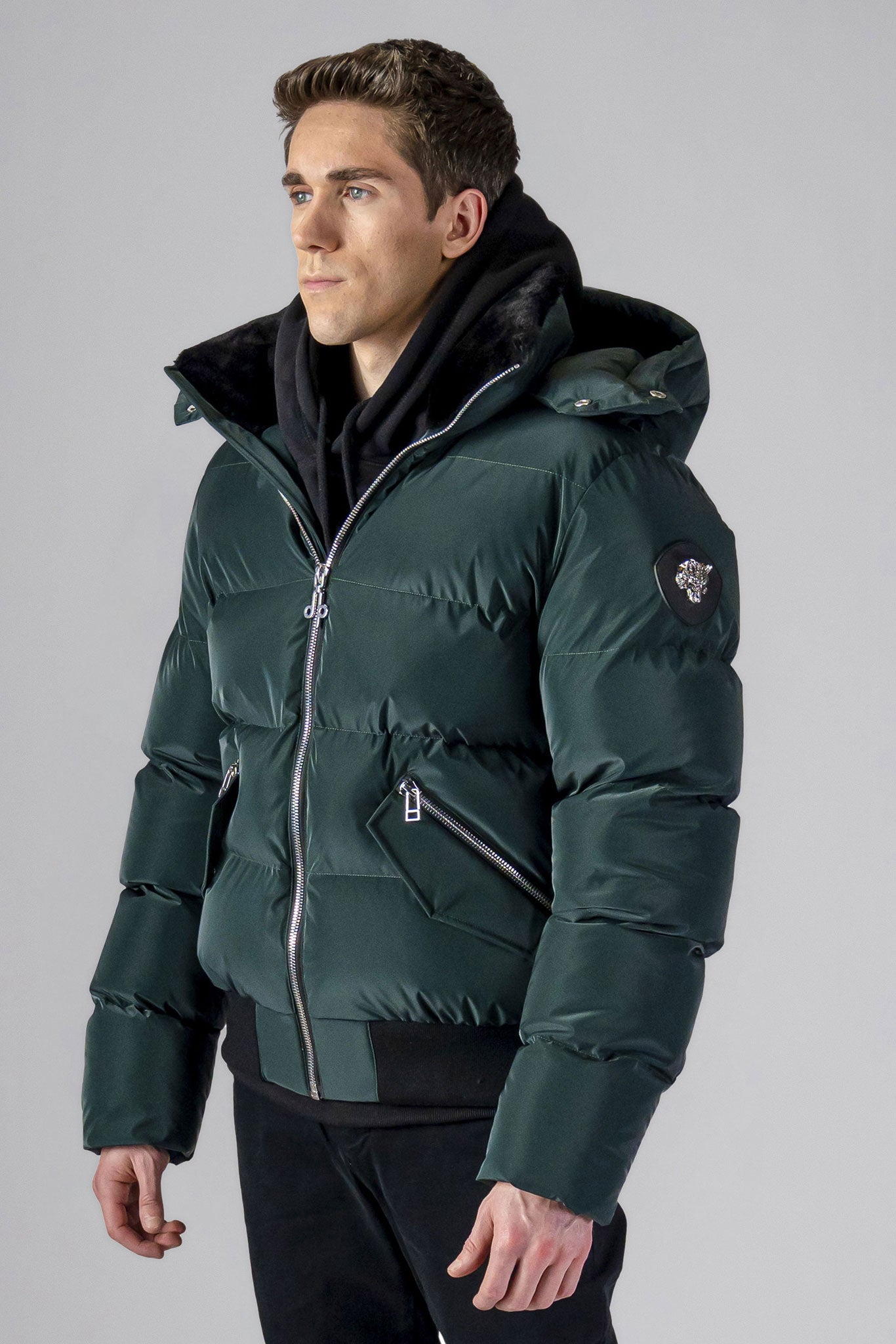 Woodpecker Men&#39;s Woody Bomber Winter coat. High-end Canadian designer winter coat for men in &quot;Green Diamond&quot; colour. Woodpecker cruelty-free winter coat designed in Canada. Men&#39;s heavy weight short length premium designer jacket for winter. Superior quality warm winter coat for men. Moose Knuckles, Canada Goose, Mackage, Montcler, Will Poho, Willbird, Nic Bayley. Shiny parka. Stylish winter jacket. Designer winter coat.