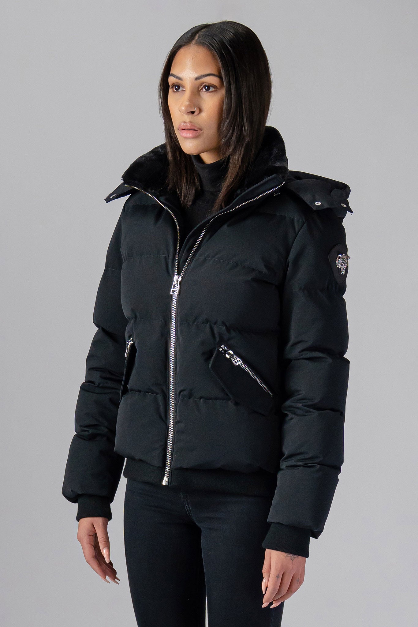 Woodpecker Women's Woody Bomber Winter coat. High-end Canadian designer winter coat for women in shiny “Matte Black" colour. Woodpecker cruelty-free winter coat designed in Canada. Women's heavy weight short length premium designer jacket for winter. Superior quality warm winter coat for women. Moose Knuckles, Canada Goose, Mackage, Montcler, Will Poho, Willbird, Nic Bayley. Shiny parka. Stylish winter jacket. Designer winter coat.